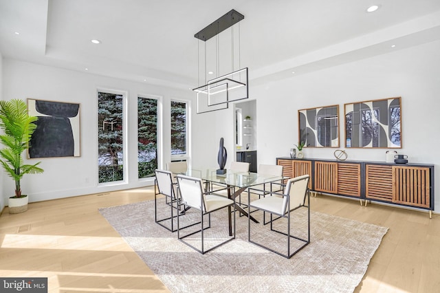 dining space with recessed lighting, baseboards, a tray ceiling, and wood finished floors