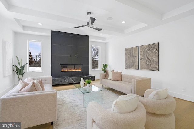 living room featuring a fireplace, recessed lighting, a raised ceiling, wood finished floors, and baseboards