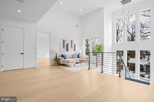 living area featuring a high ceiling, wood finished floors, an upstairs landing, and recessed lighting