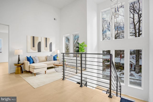 interior space featuring an upstairs landing, visible vents, a high ceiling, and wood finished floors