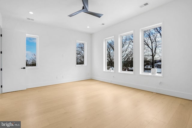 unfurnished room featuring ceiling fan, light wood-type flooring, visible vents, and baseboards