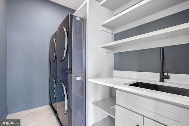 laundry room featuring stacked washer and clothes dryer, a sink, and laundry area