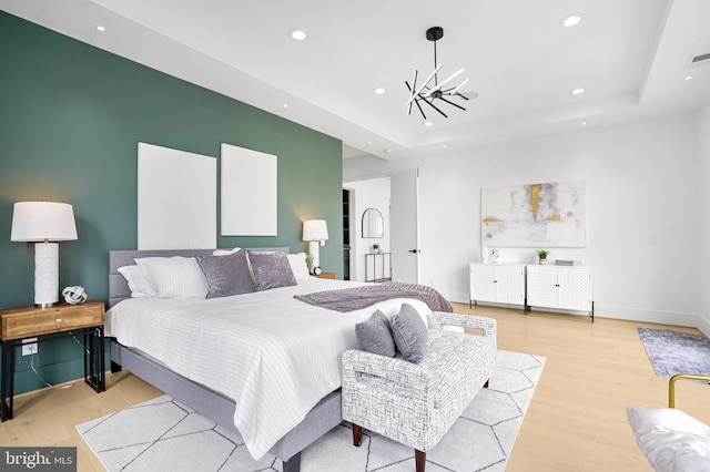 bedroom featuring a chandelier, recessed lighting, wood finished floors, baseboards, and a tray ceiling