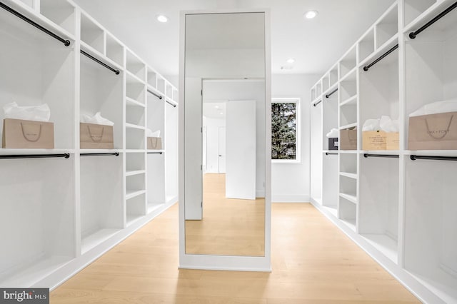 walk in closet with light wood finished floors