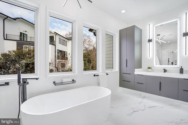 bathroom featuring marble finish floor, a shower stall, a soaking tub, and vanity