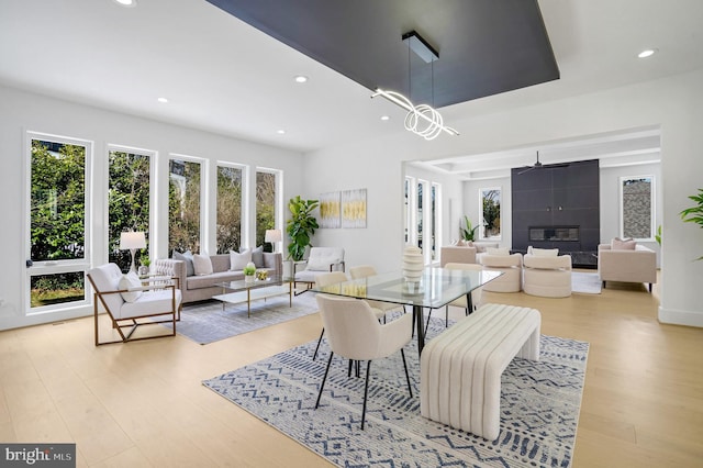 dining room featuring a tile fireplace, light wood-style flooring, and recessed lighting