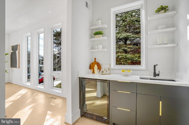 bar featuring wine cooler, plenty of natural light, a sink, and visible vents