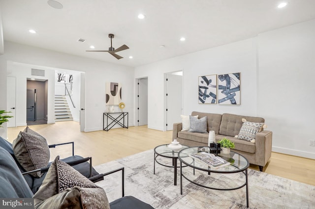 living room featuring light wood-style floors, visible vents, stairway, and recessed lighting