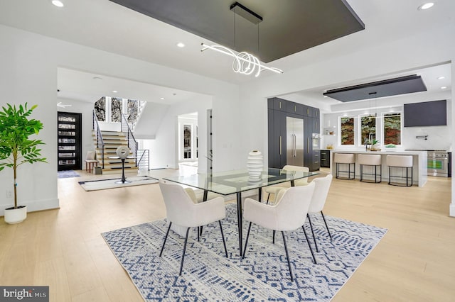 dining space with light wood-type flooring, recessed lighting, and stairs