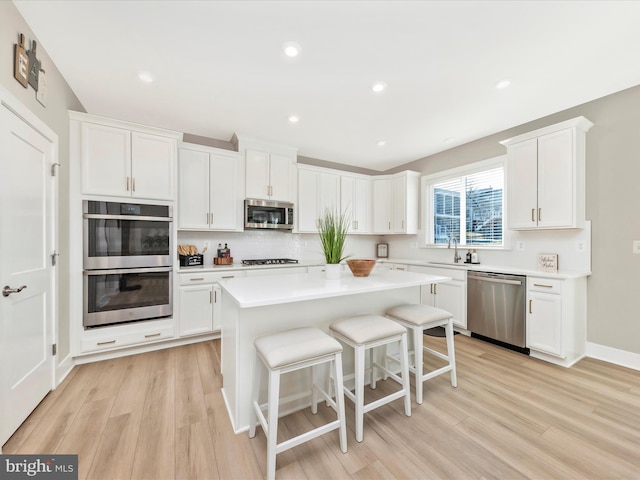 kitchen with white cabinetry, appliances with stainless steel finishes, light wood-style flooring, and light countertops