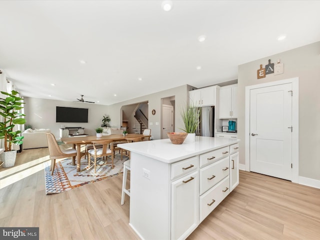 kitchen featuring light wood-style floors, a center island, white cabinetry, and freestanding refrigerator