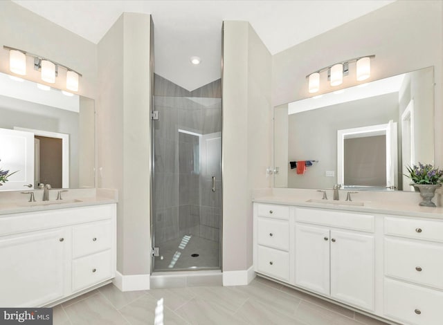 bathroom featuring a stall shower, two vanities, a sink, and baseboards