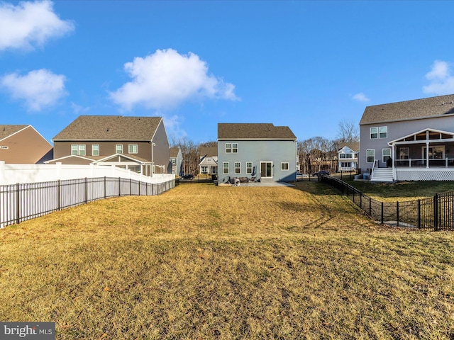 view of yard with a sunroom, a fenced backyard, and a residential view