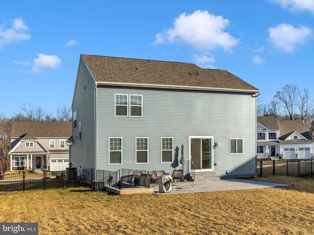 rear view of house with a yard, a shingled roof, a patio area, and fence