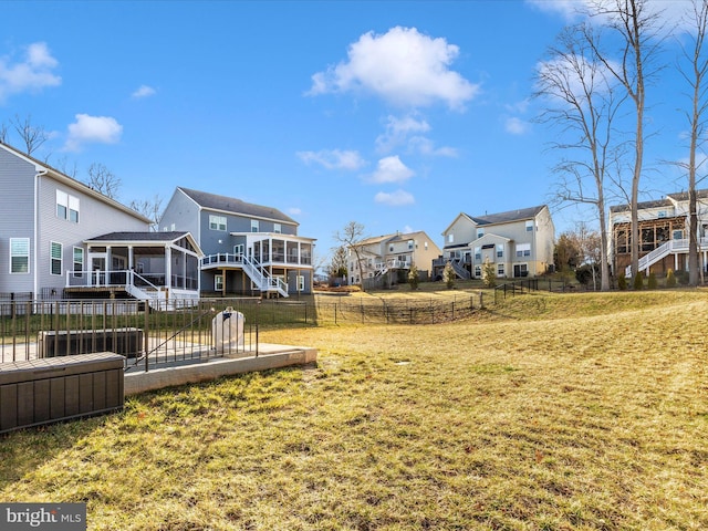 view of yard with a residential view, a sunroom, a fenced backyard, and stairway