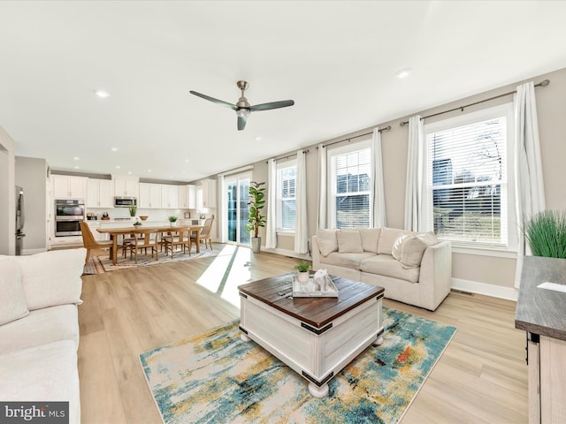 living area featuring light wood finished floors, ceiling fan, baseboards, and recessed lighting