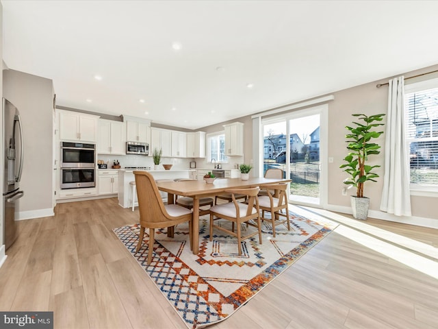 dining area with plenty of natural light, light wood-type flooring, baseboards, and recessed lighting