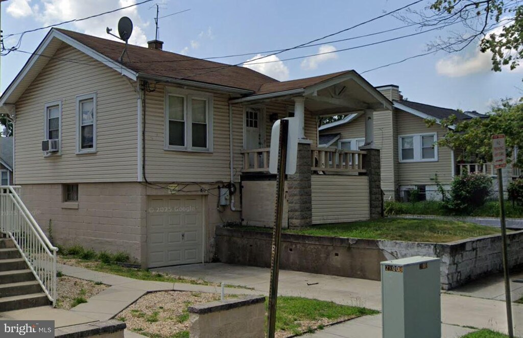 bungalow featuring a porch, stairway, and an attached garage