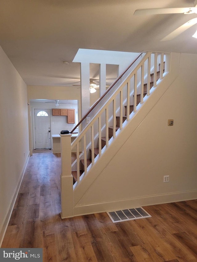 stairs featuring baseboards, wood finished floors, visible vents, and a ceiling fan