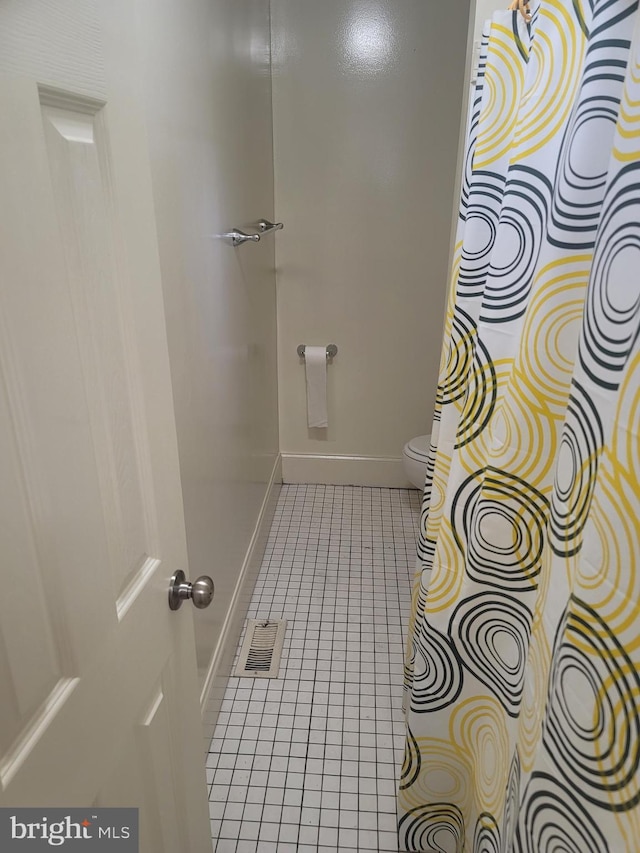 bathroom featuring toilet, visible vents, baseboards, and tile patterned floors