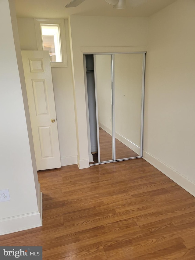 unfurnished bedroom with a closet, baseboards, and wood finished floors