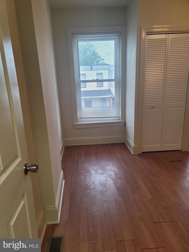 unfurnished bedroom with a closet, visible vents, baseboards, and wood finished floors