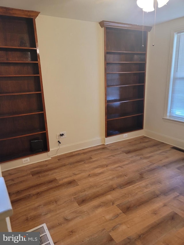 unfurnished room with wood finished floors, visible vents, and baseboards