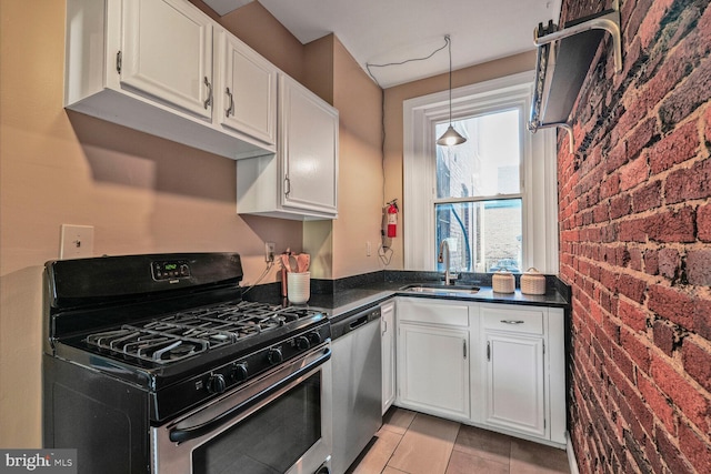 kitchen featuring brick wall, gas range oven, stainless steel dishwasher, white cabinetry, and a sink