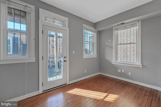 foyer entrance featuring wood finished floors, a healthy amount of sunlight, and visible vents