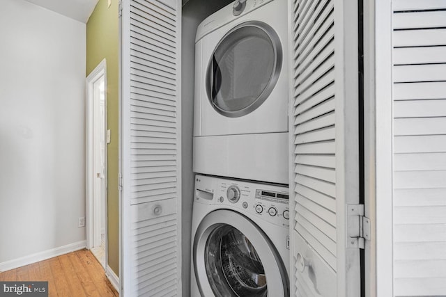 washroom with baseboards, light wood-style flooring, laundry area, and stacked washer / dryer