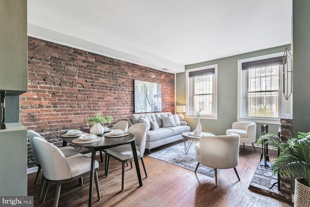 living area with hardwood / wood-style floors and brick wall