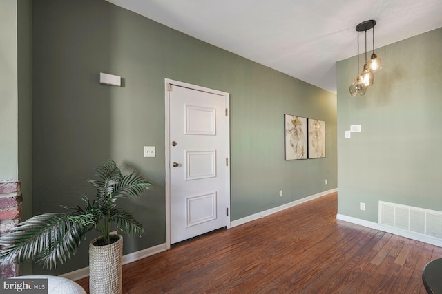 foyer entrance featuring visible vents, baseboards, and wood finished floors