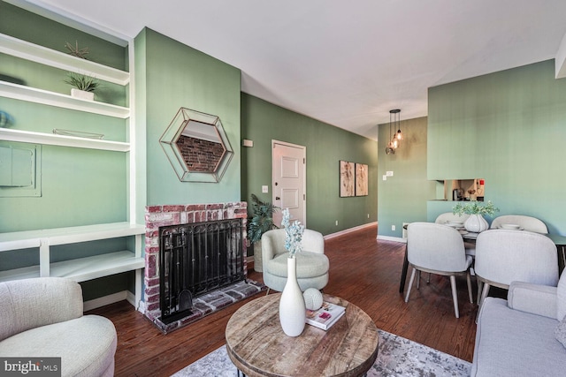 living area featuring a fireplace, baseboards, and wood finished floors