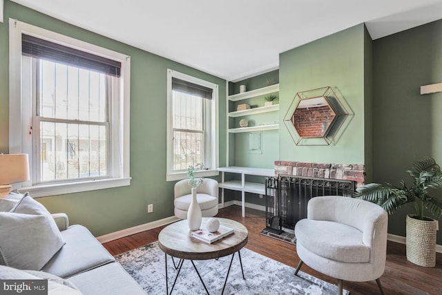 living area with built in features, wood finished floors, and baseboards