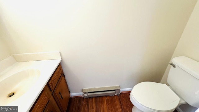 half bathroom featuring toilet, a baseboard heating unit, wood finished floors, vanity, and baseboards