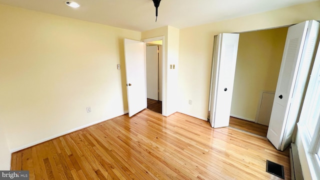 unfurnished bedroom featuring light wood-type flooring, a closet, and visible vents