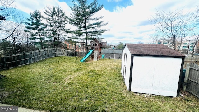 view of yard featuring an outbuilding, a storage unit, a playground, and a fenced backyard