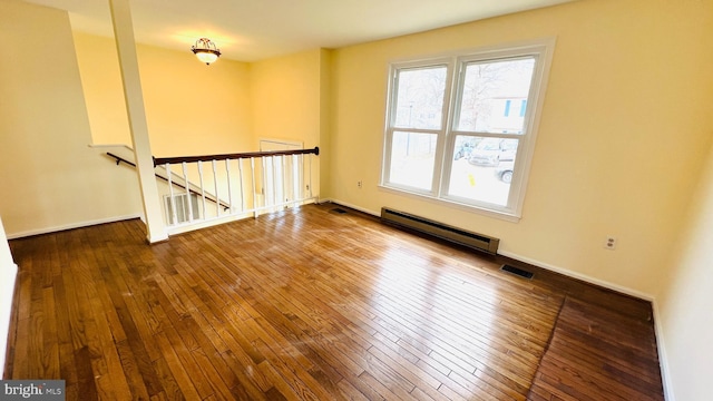 unfurnished room with a baseboard heating unit, visible vents, baseboards, and hardwood / wood-style flooring