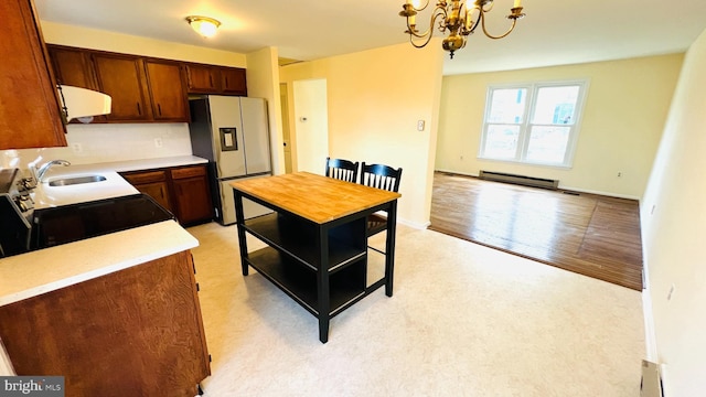 kitchen featuring light countertops, electric range, a sink, refrigerator with ice dispenser, and exhaust hood