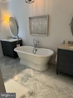 bathroom with a freestanding tub, ornamental molding, baseboards, and two vanities