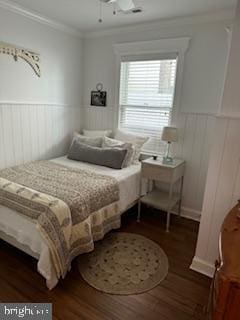 bedroom with wainscoting, crown molding, and dark wood-style flooring