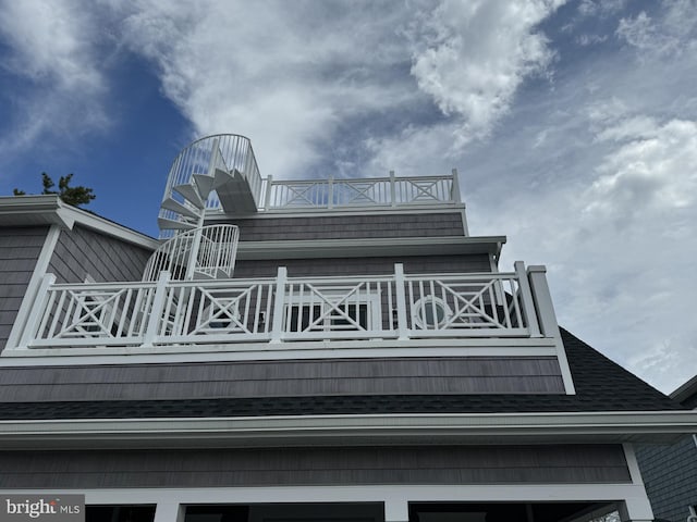 exterior space with a balcony and a shingled roof