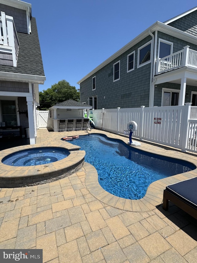 view of swimming pool featuring an outbuilding, a patio, a fenced in pool, fence, and an in ground hot tub