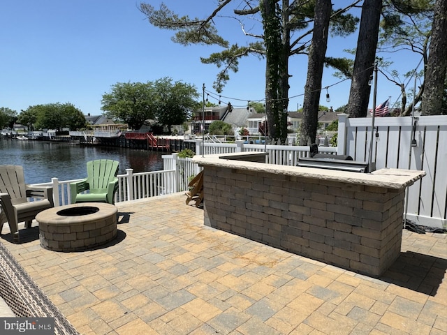 view of patio / terrace with outdoor dry bar, a fire pit, and a water view