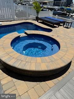 view of pool with a fenced in pool, an in ground hot tub, and fence