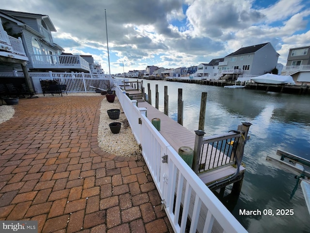 dock area featuring a water view, fence, and a residential view