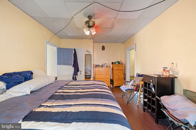 bedroom with ceiling fan, wood finished floors, and a paneled ceiling