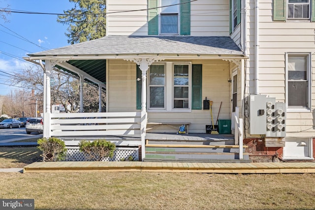 entrance to property featuring a porch and roof with shingles