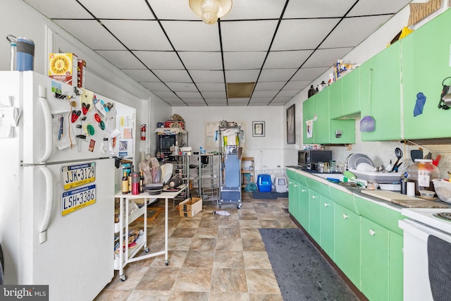 kitchen with stainless steel microwave, a wainscoted wall, light countertops, freestanding refrigerator, and a paneled ceiling