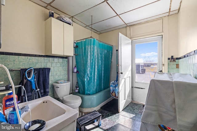 full bathroom featuring a drop ceiling, toilet, tile walls, and shower / tub combo